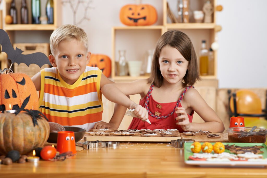 Cheerful brother and sister decorating cookies at home